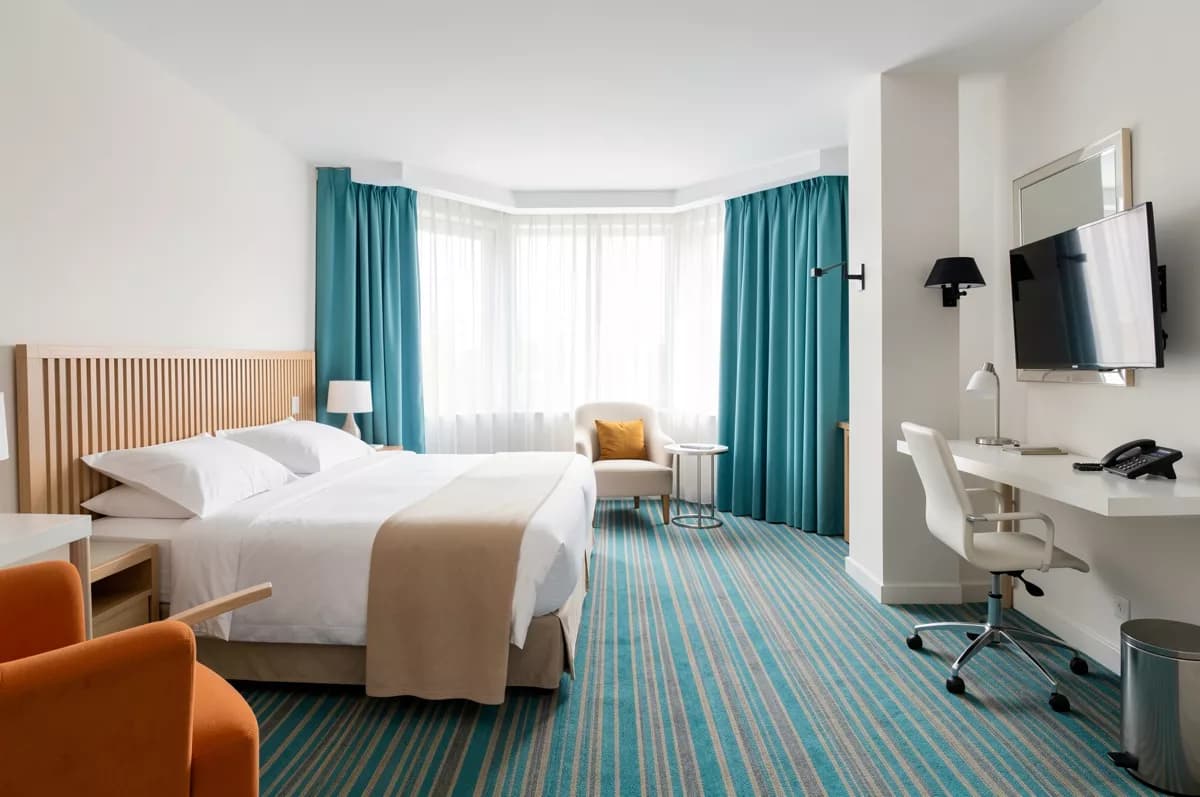 FLUX.2 Klein — Interior: A spacious modern hotel room. A double bed with a pale wood slatted headboard, c