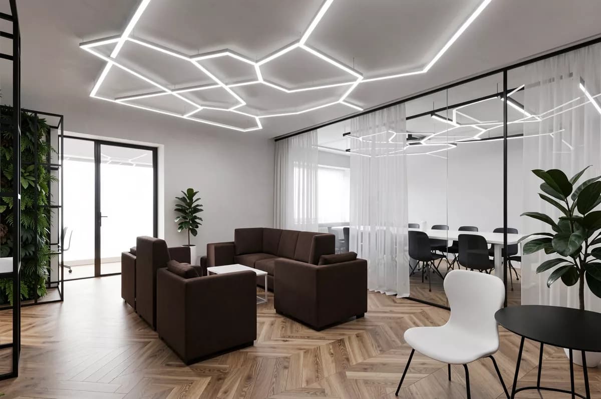 Interior: An open-plan office lounge. Overhead, a large angular ceiling installation of in