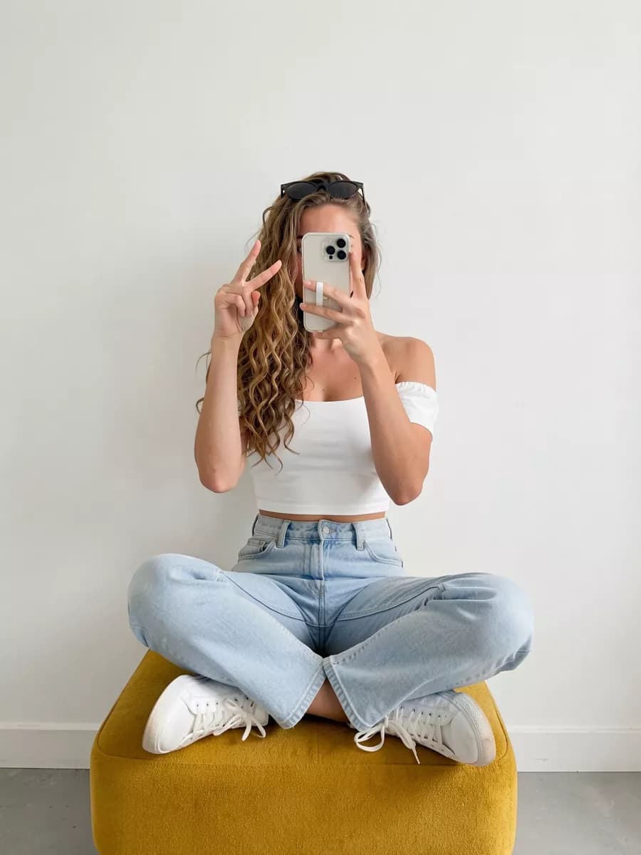 Social marketing: A young woman photographs herself in a mirror against a plain white wall. She si