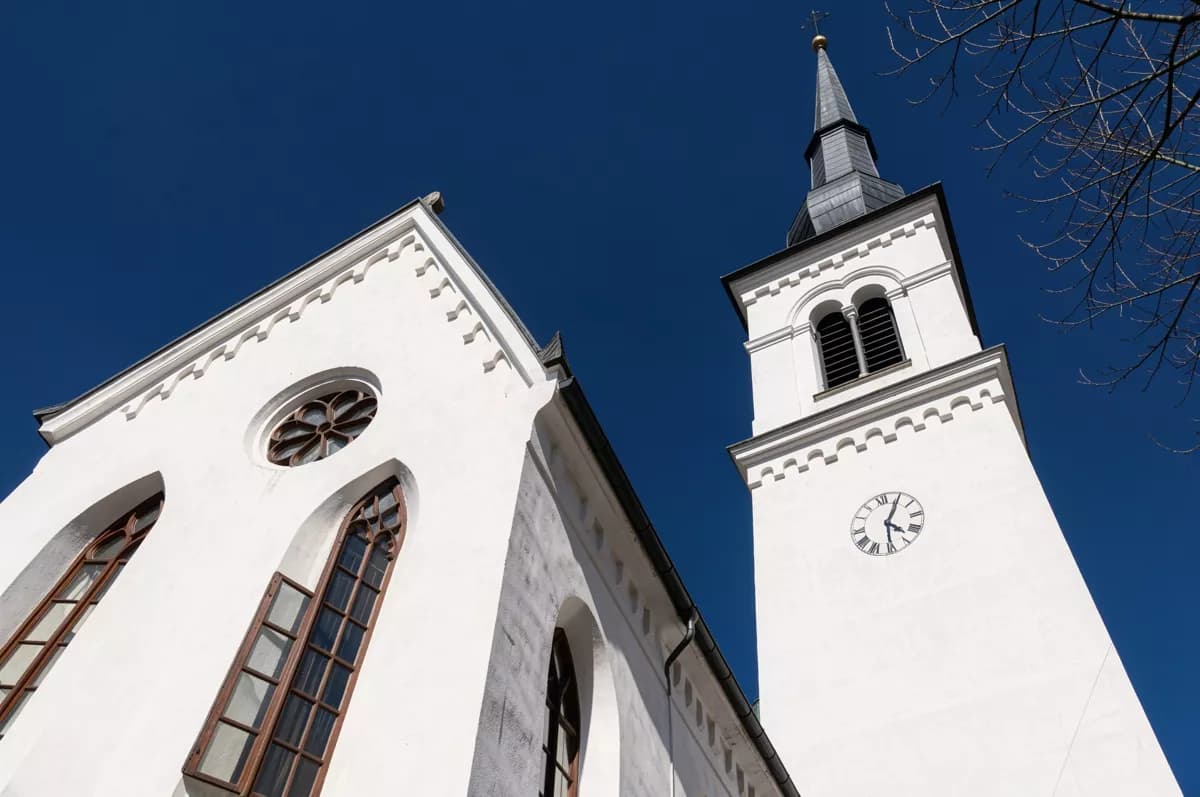 Street and architecture: A white plastered church seen from directly below against a cloudless deep blue 