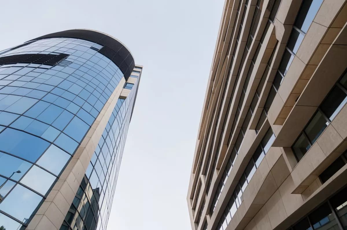 Street and architecture: Two modern office towers photographed from the pavement looking straight up, wit