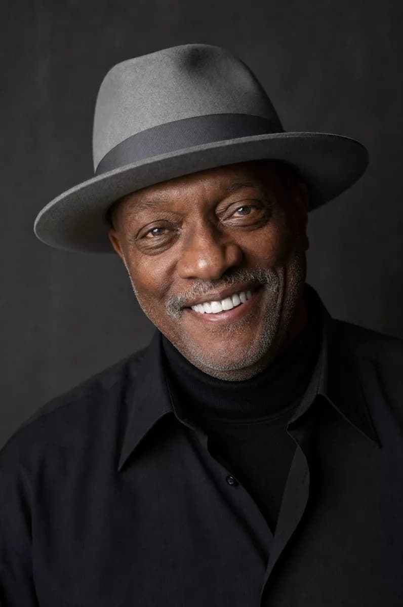 Fashion and beauty: A studio portrait of a Black man in his sixties smiling broadly at the camera, h