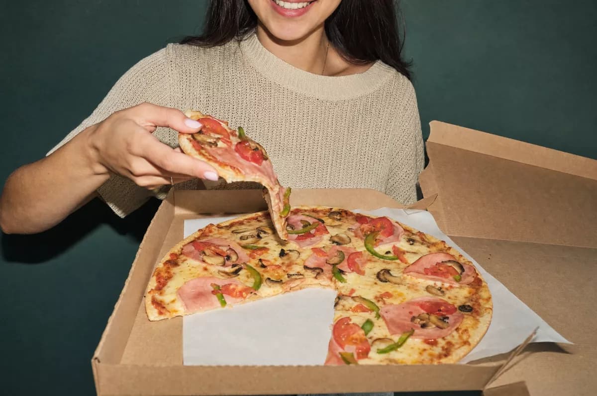 GPT Image 2 — Food and beverage: A young woman with dark hair in a beige knitted t-shirt holds an open kraft card
