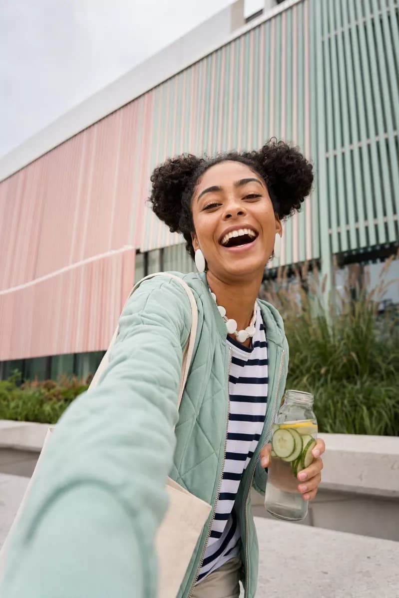 Social marketing: A low-angle outdoor selfie of a young woman with dark curly hair in two afro puf