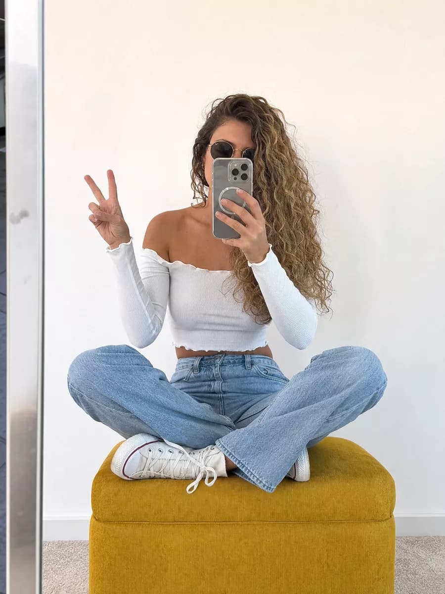Social marketing: A young woman photographs herself in a mirror against a plain white wall. She si