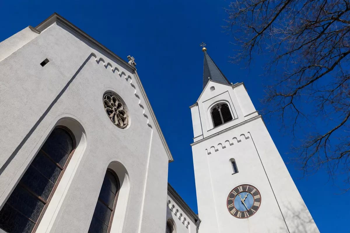 Street and architecture: A white plastered church seen from directly below against a cloudless deep blue 