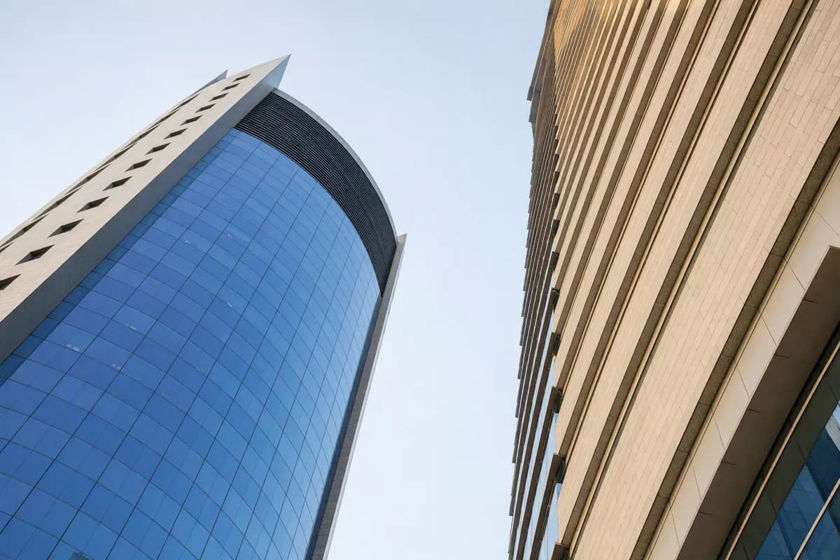 Street and architecture: Two modern office towers photographed from the pavement looking straight up, wit