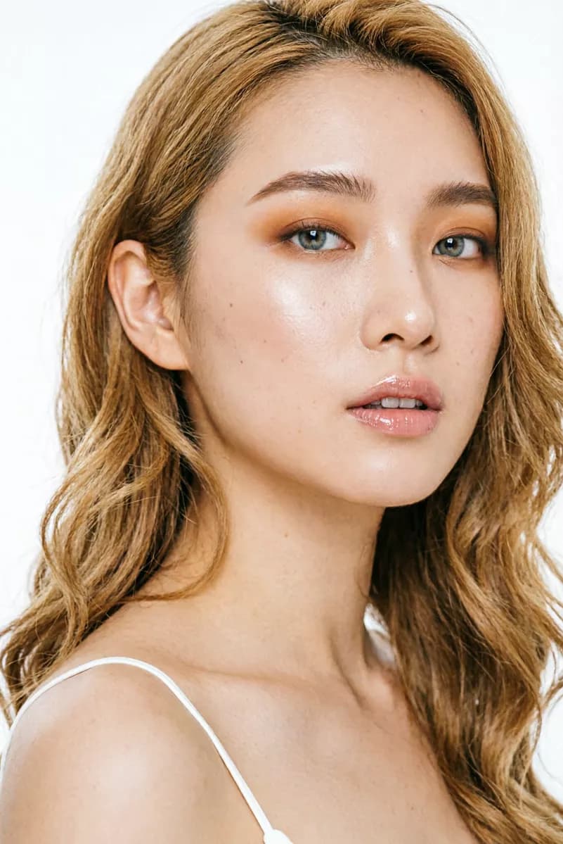 Fashion and beauty: A beauty close-up of a young woman with long wavy honey-blonde hair against a pl