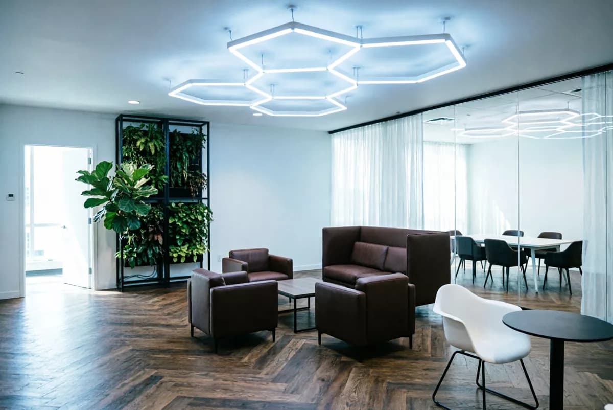 Interior: An open-plan office lounge. Overhead, a large angular ceiling installation of in
