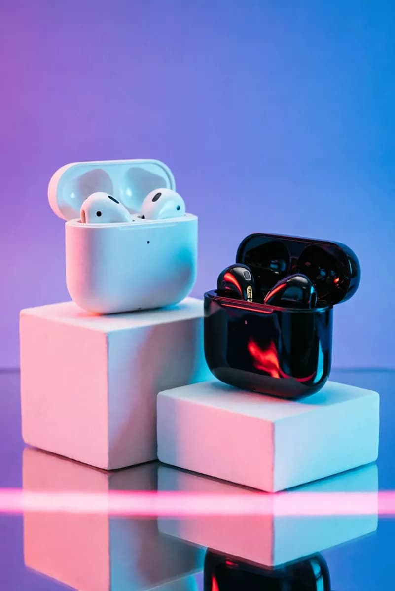 Qwen Image 2.0 — Product and e-commerce: Two wireless earbud charging cases displayed on white geometric podiums, both op