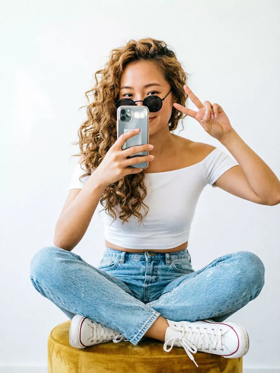 Social marketing: A young woman photographs herself in a mirror against a plain white wall. She si