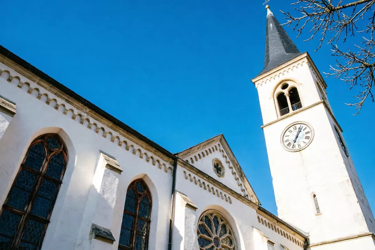 Street and architecture: A white plastered church seen from directly below against a cloudless deep blue 