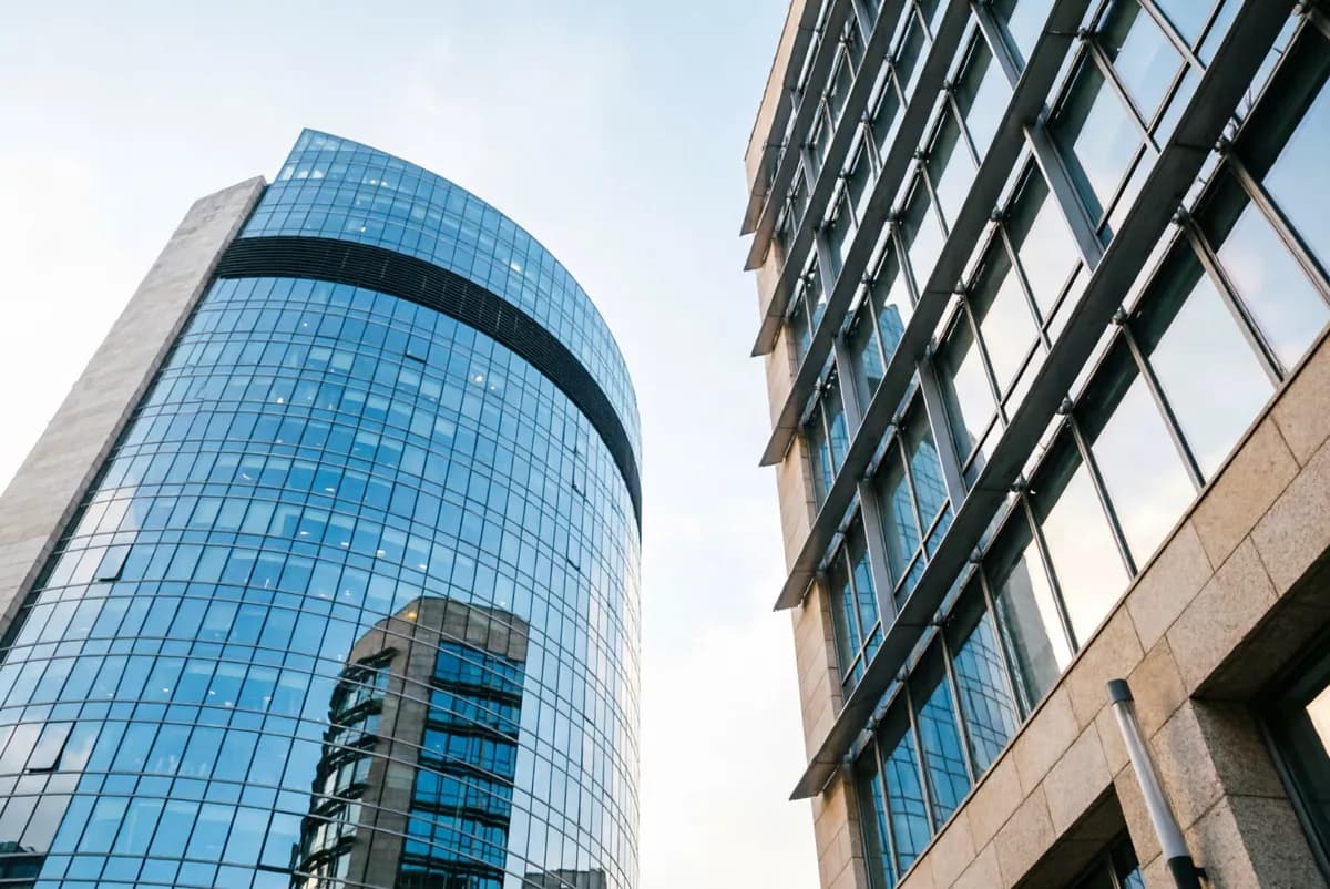 Street and architecture: Two modern office towers photographed from the pavement looking straight up, wit