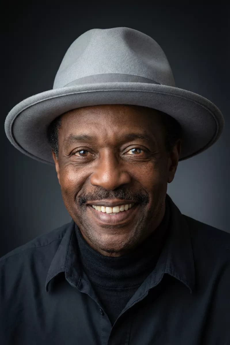 Fashion and beauty: A studio portrait of a Black man in his sixties smiling broadly at the camera, h