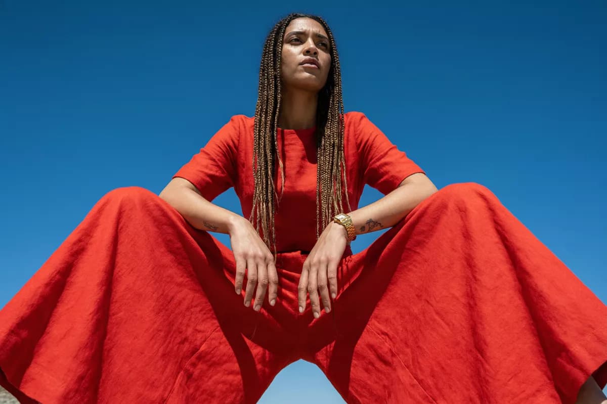 Qwen Image 2.0 Pro — Fashion and beauty: A fashion portrait shot from far below against a cloudless deep blue sky. A woma