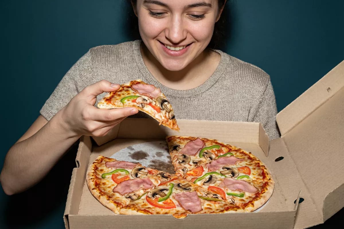 Qwen Image 2.0 Pro — Food and beverage: A young woman with dark hair in a beige knitted t-shirt holds an open kraft card