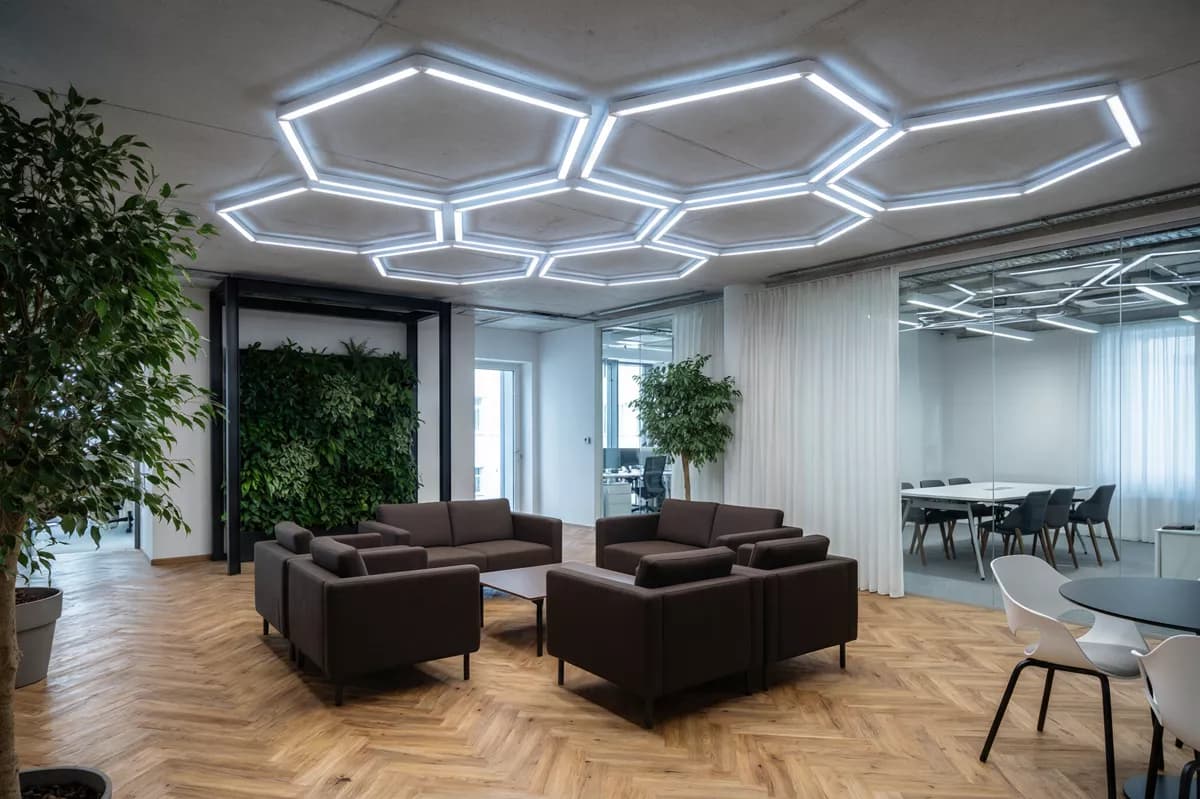 Qwen Image 2.0 Pro — Interior: An open-plan office lounge. Overhead, a large angular ceiling installation of in