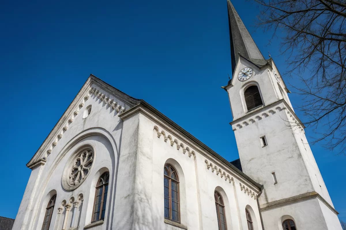 Street and architecture: A white plastered church seen from directly below against a cloudless deep blue 