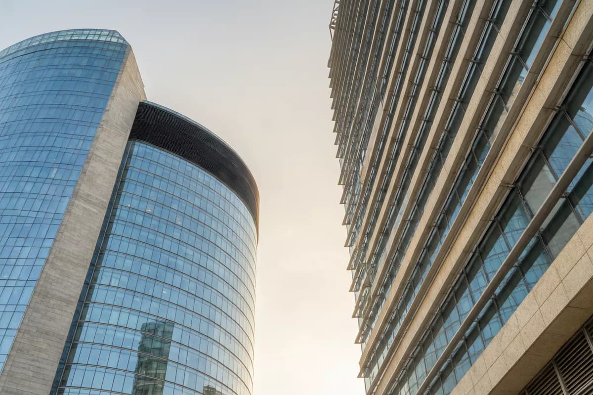 Street and architecture: Two modern office towers photographed from the pavement looking straight up, wit