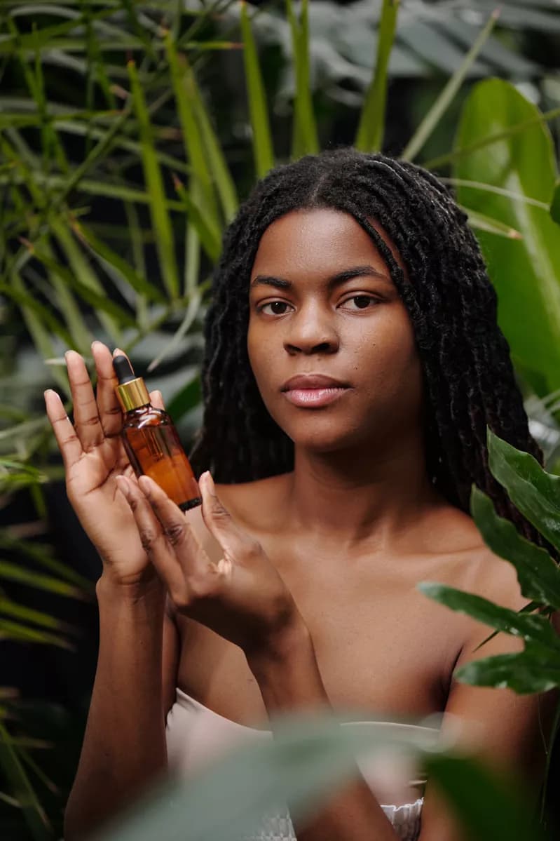 Real photograph — Fashion and beauty: A Black woman with long locs, bare shoulders and a strapless cream top stands am