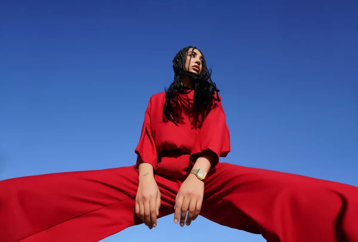 Real photograph — Fashion and beauty: A fashion portrait shot from far below against a cloudless deep blue sky. A woma
