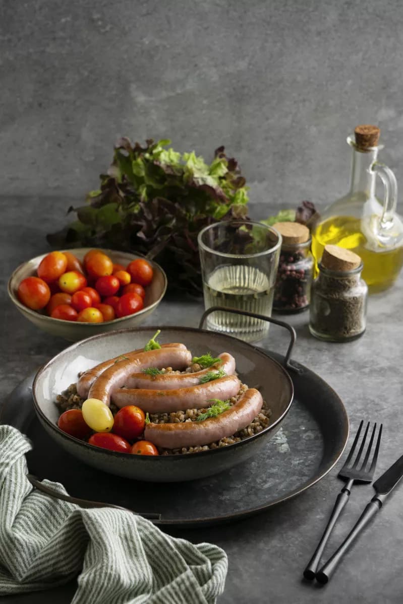 Real photograph — Food and beverage: A rustic still life on a grey concrete surface: a dark ceramic bowl on a black m