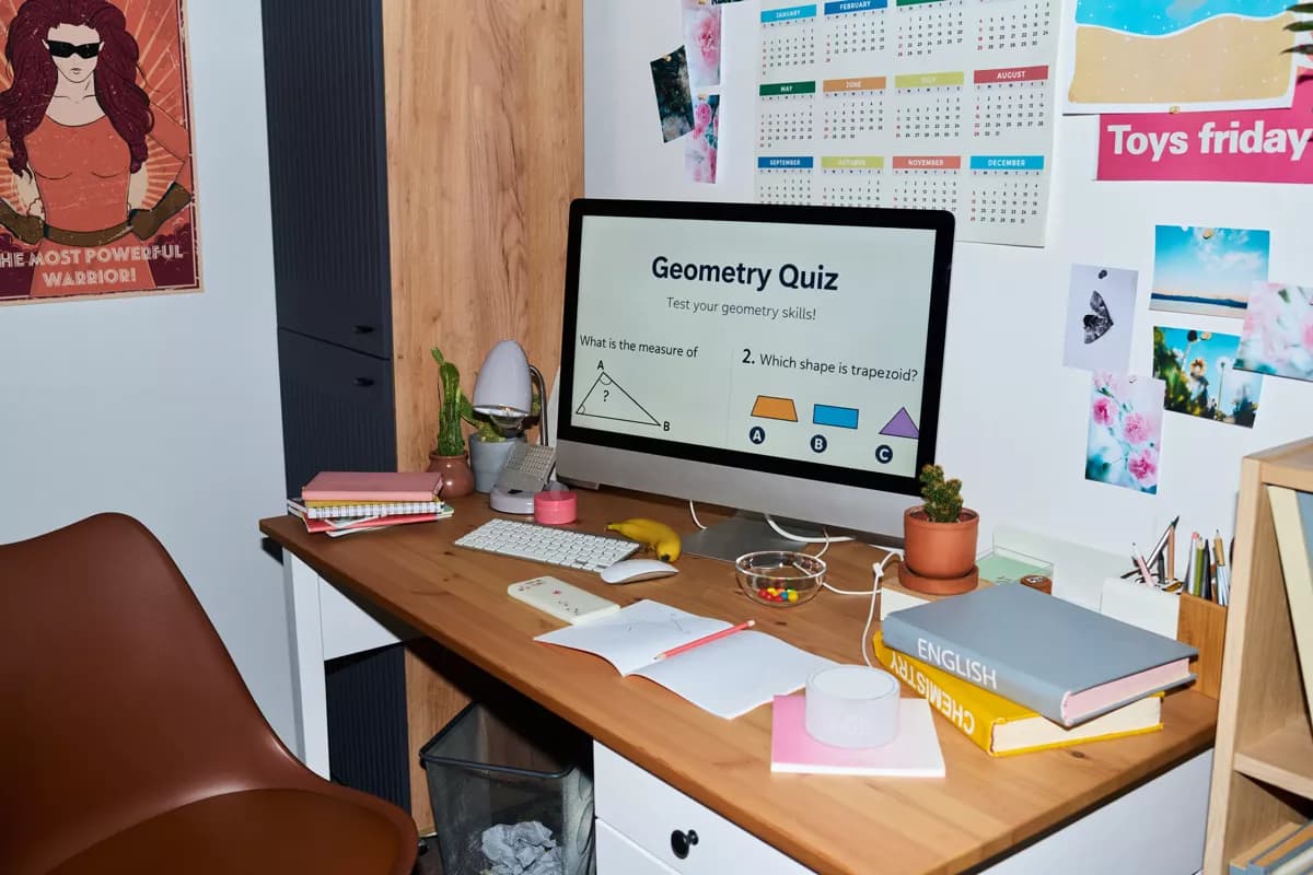 Real photograph — Layout and typography: A teenager's home study corner. A silver all-in-one computer on a wooden desk sh