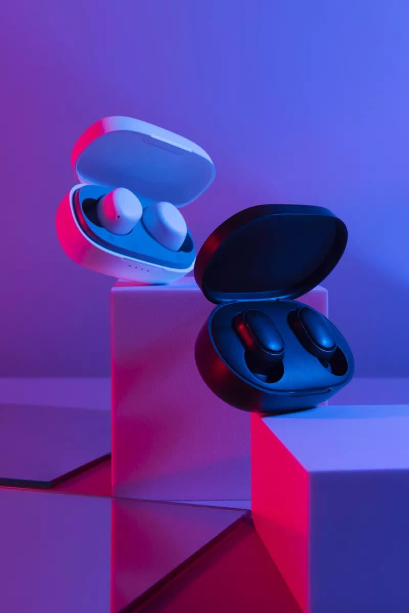 Real photograph — Product and e-commerce: Two wireless earbud charging cases displayed on white geometric podiums, both op