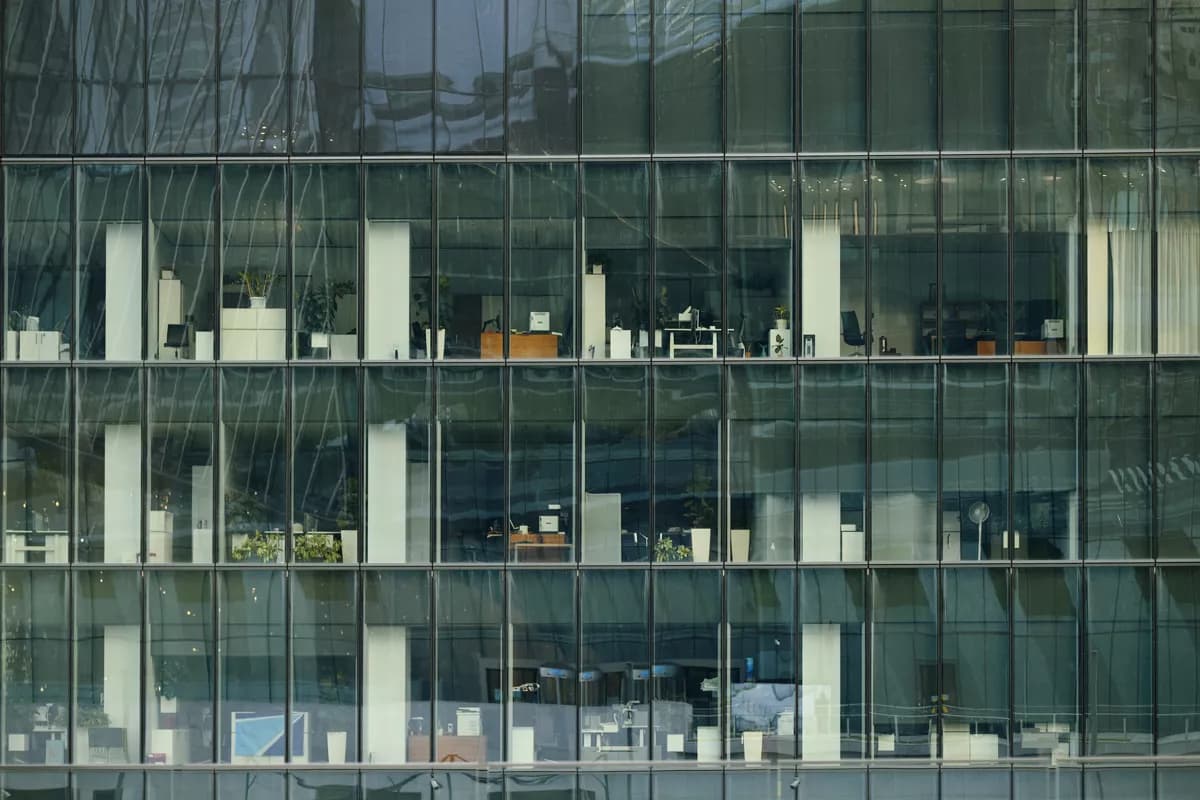 Real photograph — Street and architecture: A flat frontal telephoto view of part of a glass office tower facade, filling th
