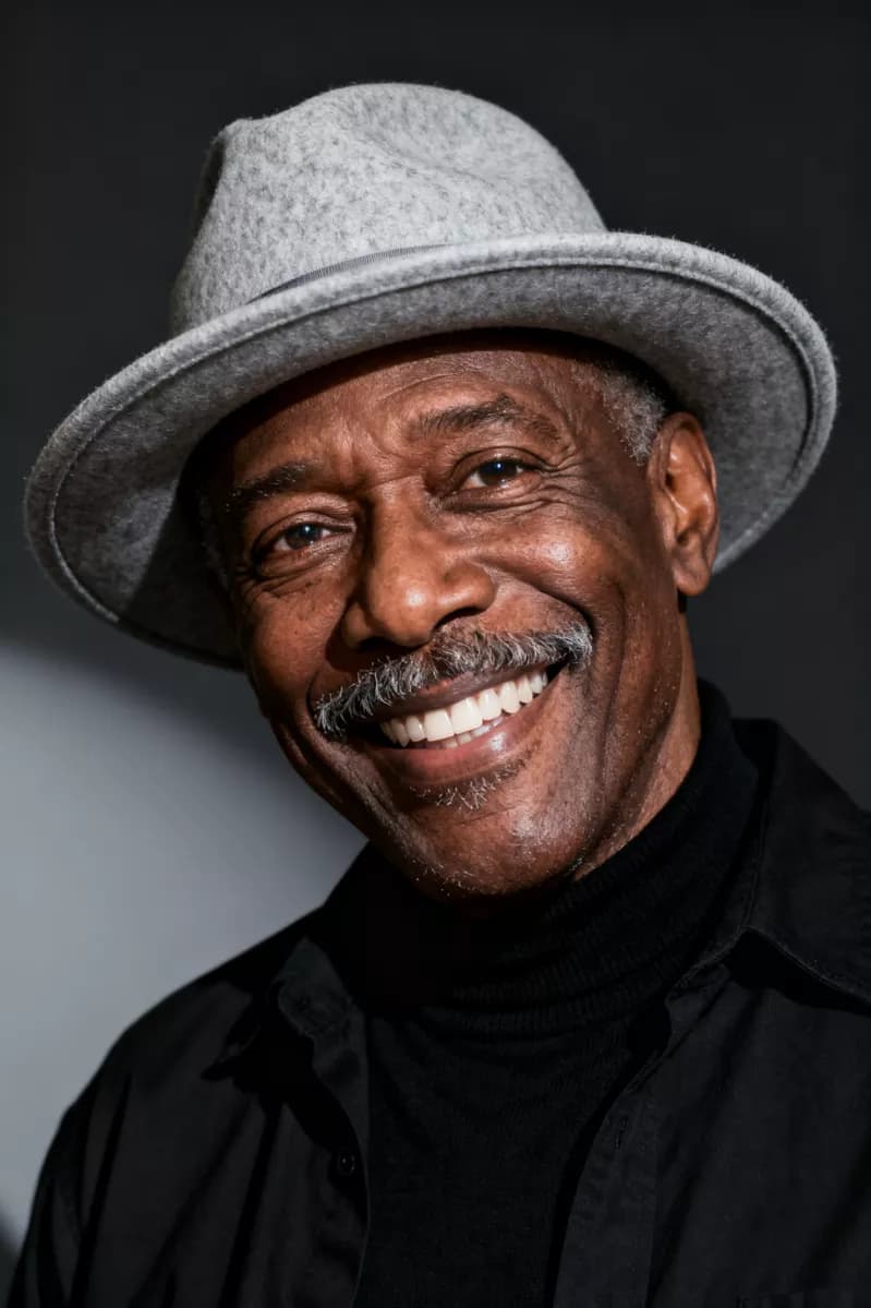 Fashion and beauty: A studio portrait of a Black man in his sixties smiling broadly at the camera, h