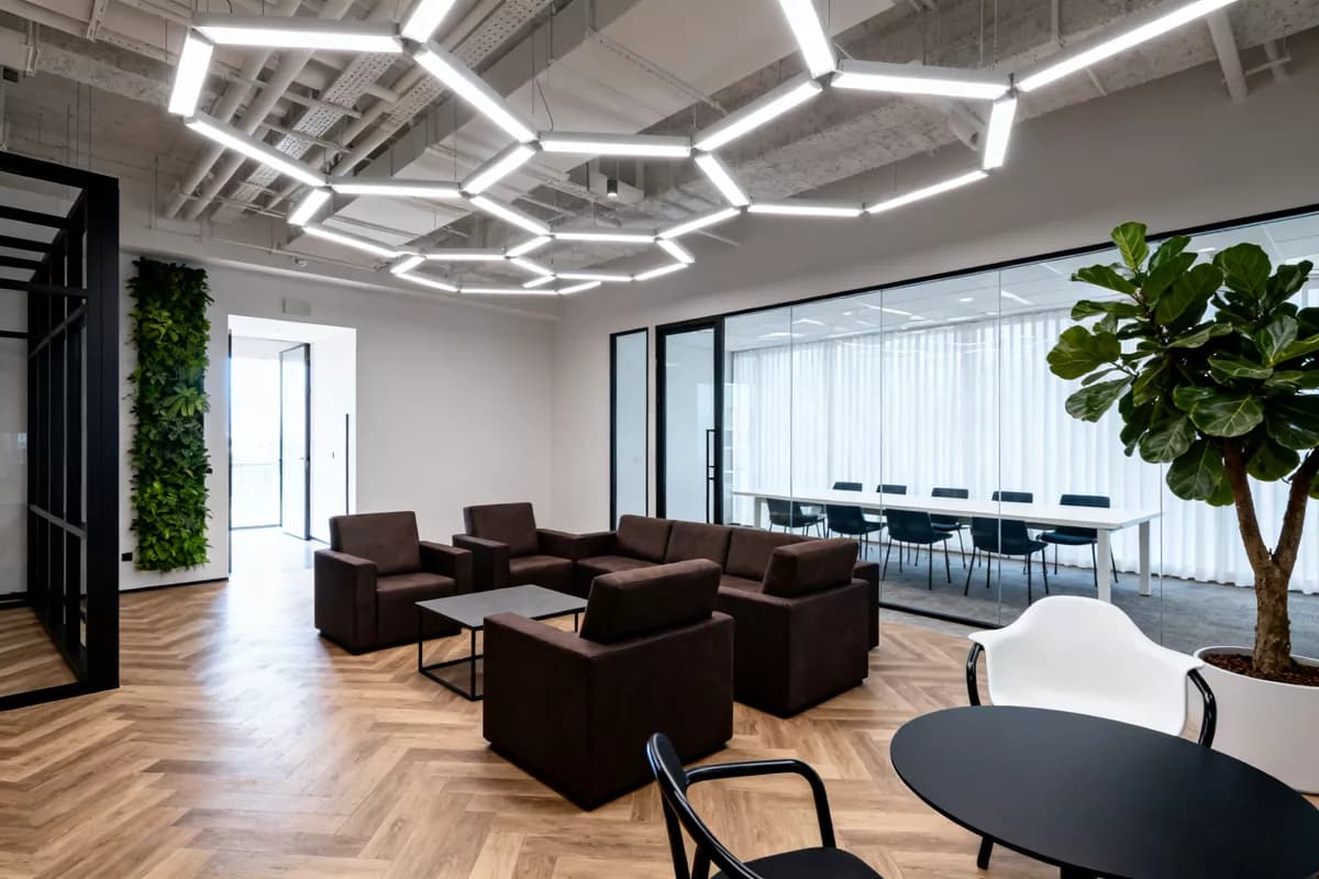 Seedream 4.0 — Interior: An open-plan office lounge. Overhead, a large angular ceiling installation of in