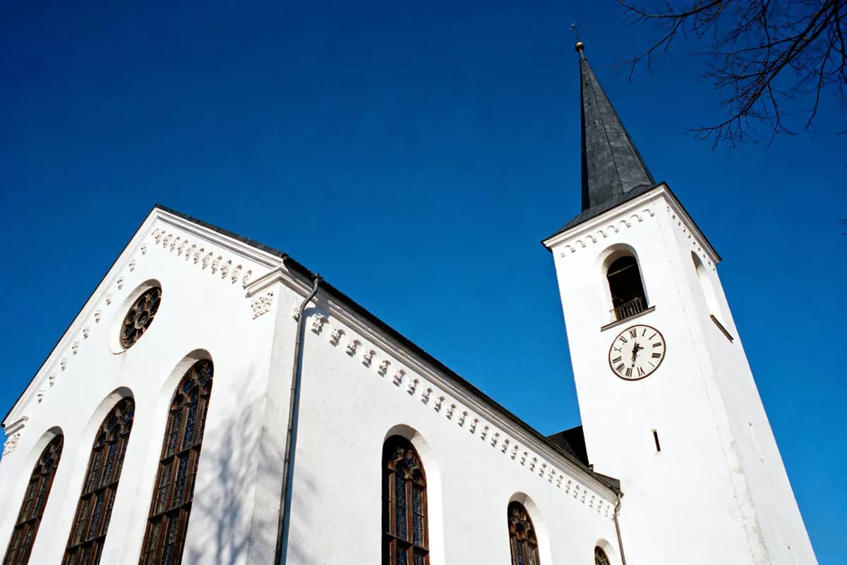 Street and architecture: A white plastered church seen from directly below against a cloudless deep blue 