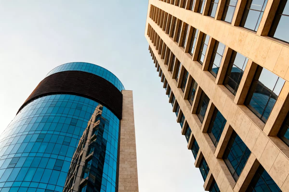 Street and architecture: Two modern office towers photographed from the pavement looking straight up, wit